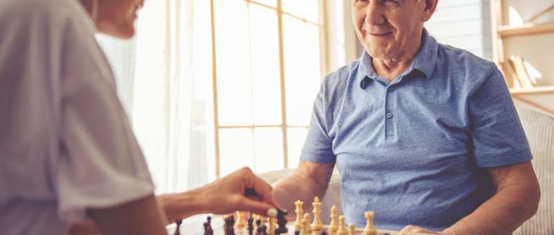 caregiver and senior playing chess