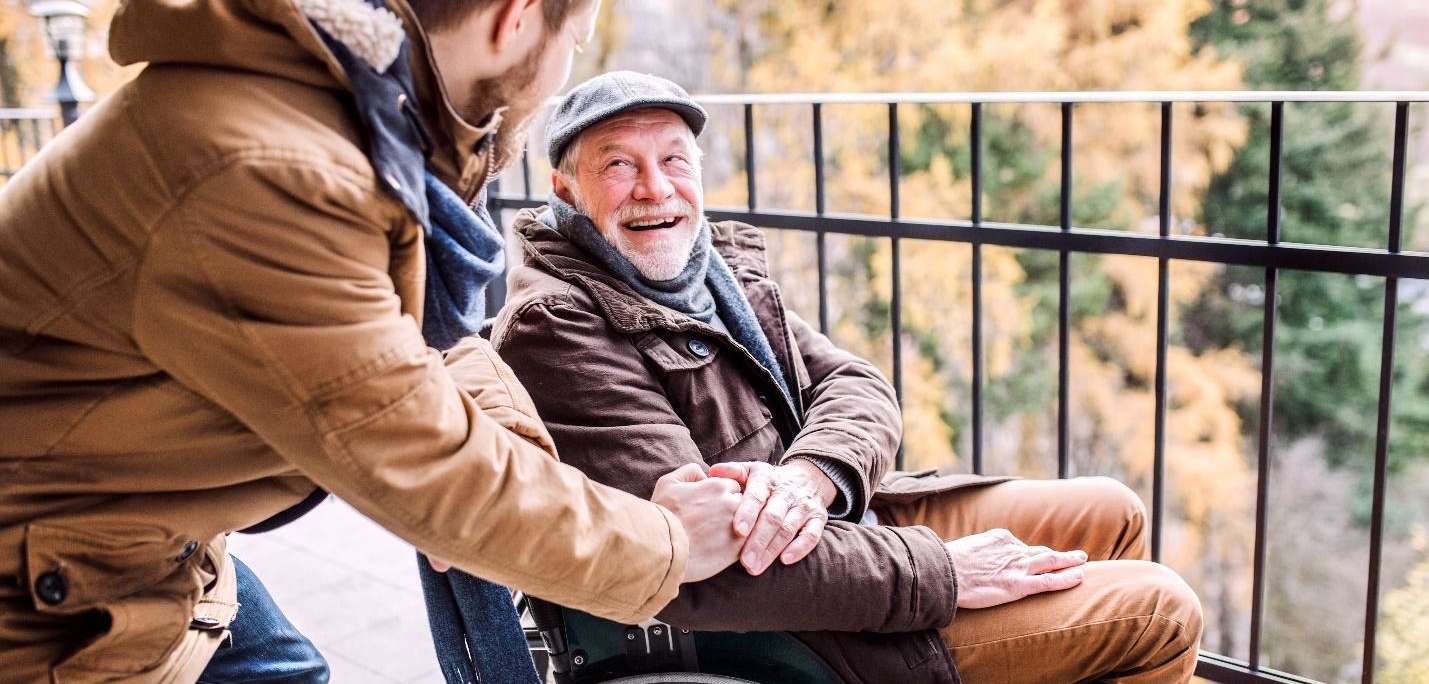 a caregiver assisting an elderly man in a wheelchair