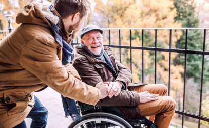 a caregiver assisting an elderly man in a wheelchair