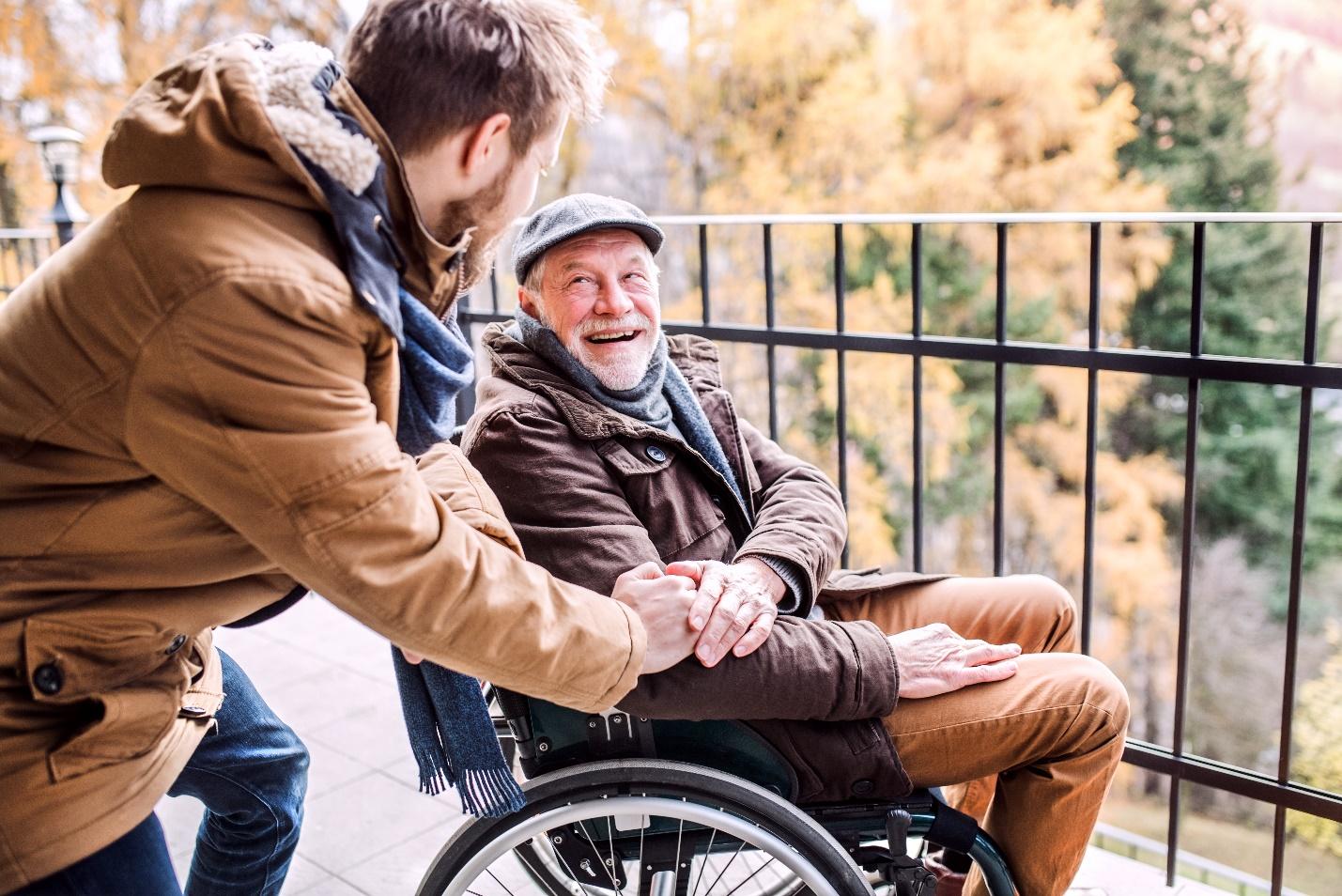 a caregiver assisting an elderly man in a wheelchair