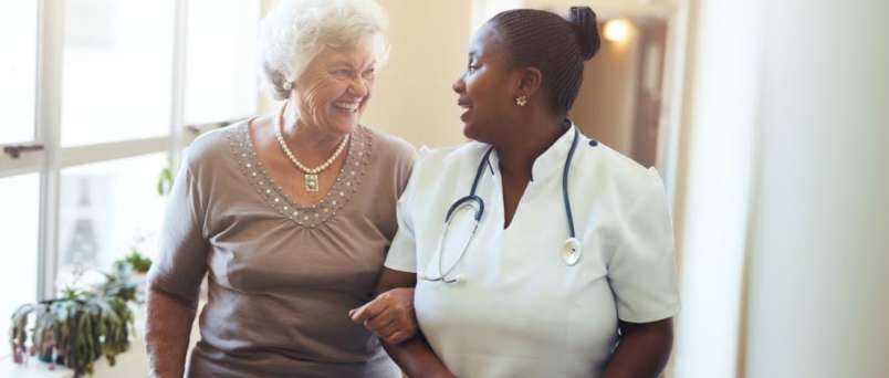 a caregiver and senior sharing a laugh arm in arm