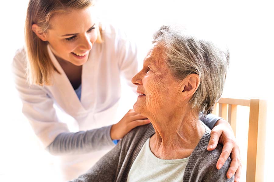 Caregiver placing arms around a seated senior