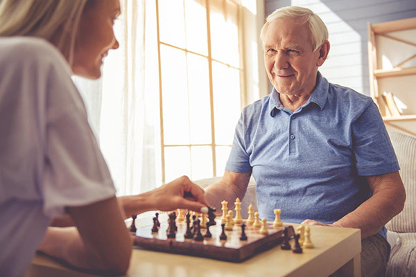 a caregiver and elderly man playing chess