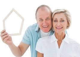 an elderly couple holding Popsicle sticks in the shape of a house