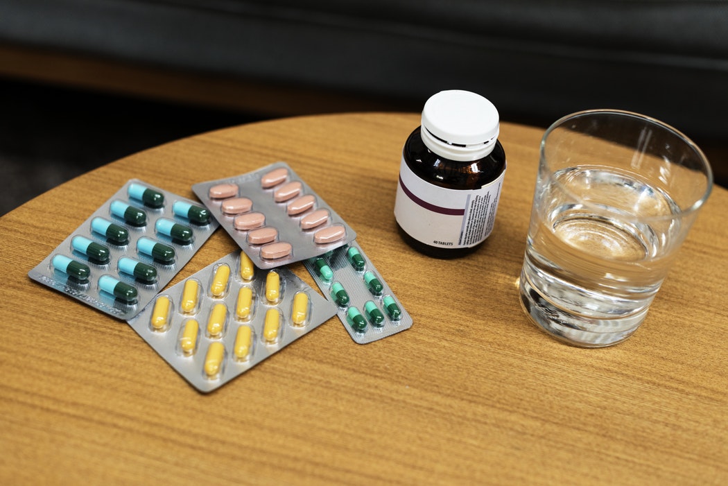 a table full of pills in their package with a glass of water
